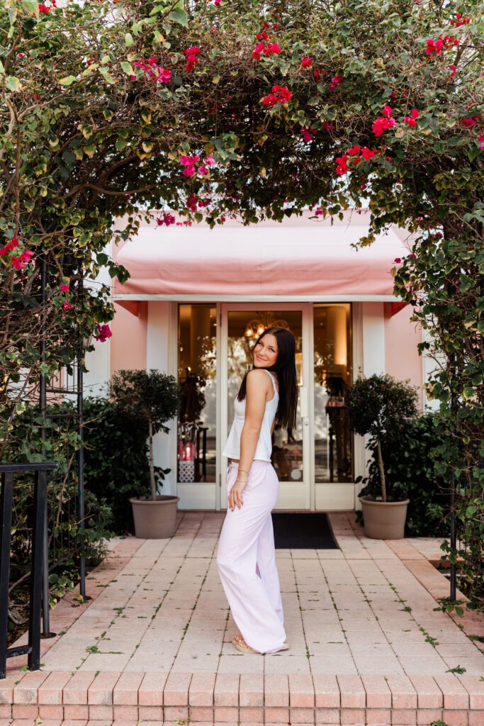 Senior portrait session at a pink storefront in Olde Naples